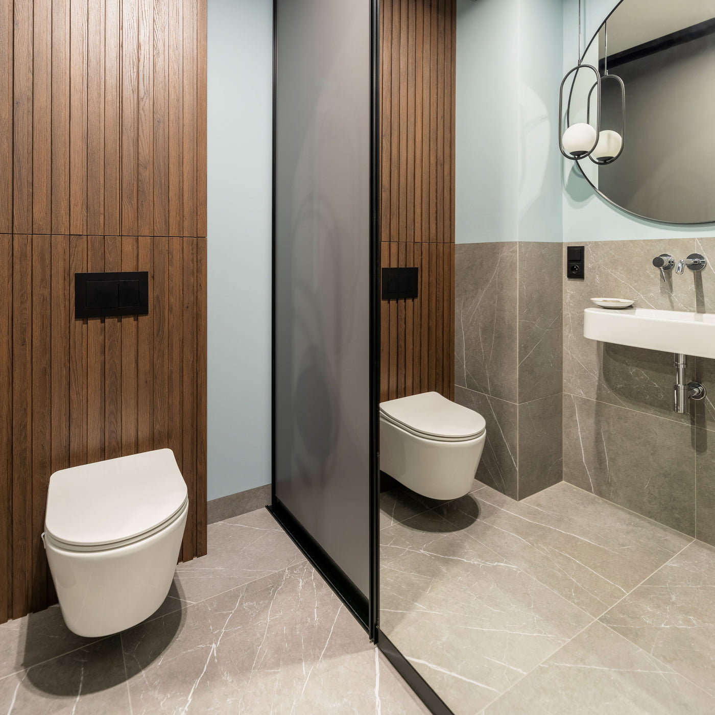 A finished bathroom with a wall hung toilet, a dark shower screen and a wall mounted basin